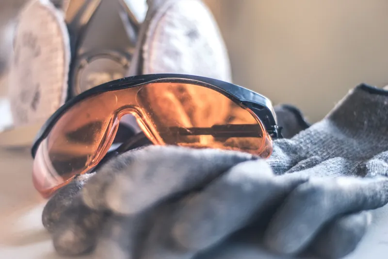 Orange-tinted safety goggles, work gloves and a respirator laid together