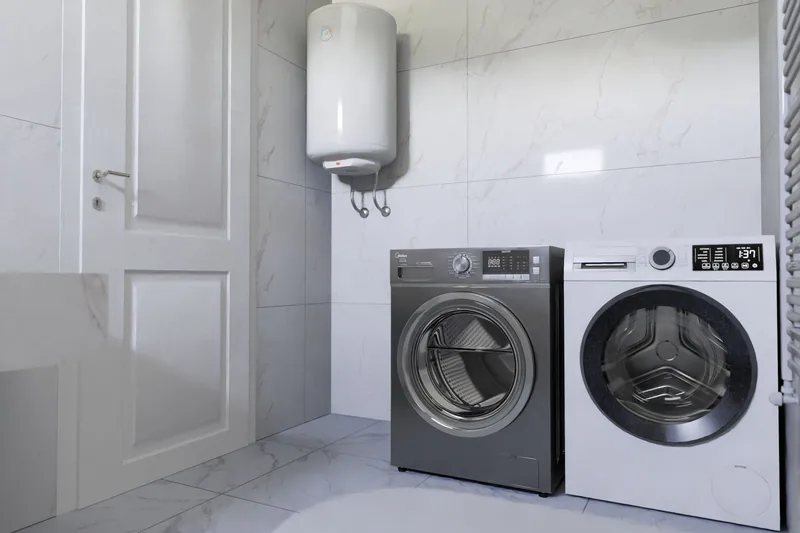 Tiled utility room with a wall-mounted water heater and two washing machines